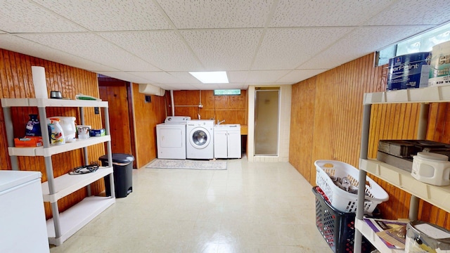 10 Covell Ave NW, Grand Rapids, MI 49504 - below grade area featuring washing machine and clothes dryer, wooden walls, white refrigerator, and a drop ceiling