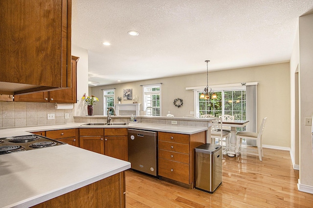 7853 Clydesdale Ave, Kalamazoo, MI 49009 - kitchen with stainless steel dishwasher, brown cabinets, light wood-type flooring, light countertops, and a peninsula