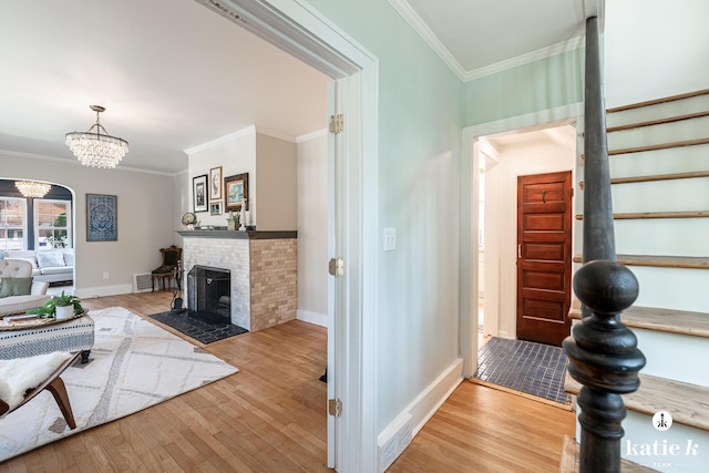 1002 Benjamin Ave SE, Grand Rapids, MI 49506 - living room featuring crown molding, wood finished floors, a chandelier, and a brick fireplace