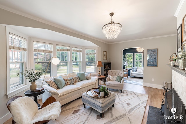 1002 Benjamin Ave SE, Grand Rapids, MI 49506 - living room featuring ornamental molding, wood finished floors, a fireplace with flush hearth, a chandelier, and arched walkways