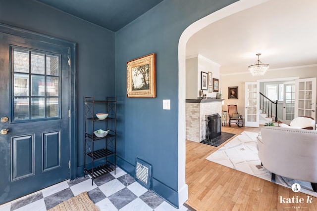 1002 Benjamin Ave SE, Grand Rapids, MI 49506 - entryway featuring arched walkways, stairs, a fireplace with flush hearth, a chandelier, and ornamental molding
