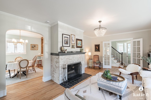 1002 Benjamin Ave SE, Grand Rapids, MI 49506 - living room featuring a chandelier, light wood-type flooring, crown molding, arched walkways, and a fireplace