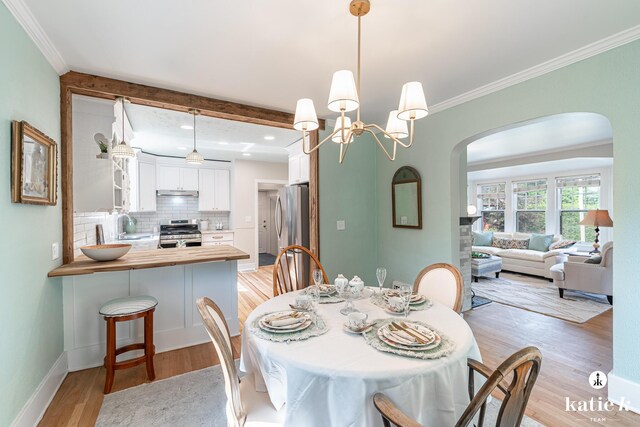 1002 Benjamin Ave SE, Grand Rapids, MI 49506 - dining room with arched walkways, light wood finished floors, ornamental molding, recessed lighting, and a chandelier