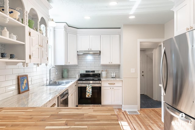 1002 Benjamin Ave SE, Grand Rapids, MI 49506 - kitchen with appliances with stainless steel finishes, under cabinet range hood, light wood-type flooring, open shelves, and white cabinets