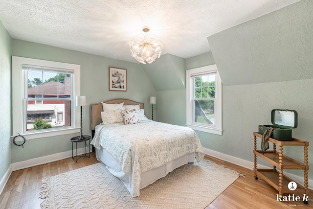 1002 Benjamin Ave SE, Grand Rapids, MI 49506 - bedroom with wood finished floors, a chandelier, a textured ceiling, and vaulted ceiling