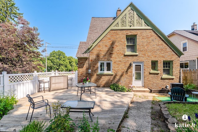 1002 Benjamin Ave SE, Grand Rapids, MI 49506 - rear view of property featuring a wooden deck, a shingled roof, brick siding, and a chimney