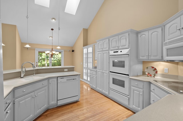 6916 Windsong Way, Kalamazoo, MI 49009 - kitchen featuring white appliances, a skylight, light wood-style floors, light countertops, and high vaulted ceiling