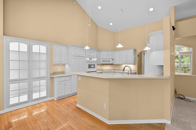 6916 Windsong Way, Kalamazoo, MI 49009 - kitchen featuring white appliances, high vaulted ceiling, light countertops, a peninsula, and light wood finished floors