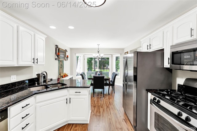 13563 Trotters Ln, Sterling Heights, MI 48313 - kitchen featuring appliances with stainless steel finishes, light wood-style flooring, white cabinetry, a peninsula, and dark stone countertops