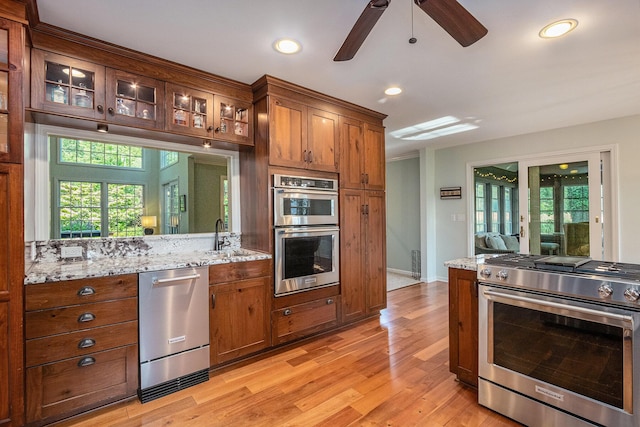 1415 Blackhawk Trl, Benton Harbor, MI 49022 - kitchen with stainless steel appliances, light wood-style flooring, ceiling fan, glass insert cabinets, and light stone counters