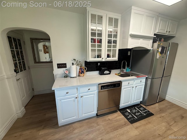 6715 Elizabeth Lake Rd, Waterford, MI 48327 - kitchen featuring stainless steel appliances, light wood-style floors, white cabinets, tasteful backsplash, and glass insert cabinets