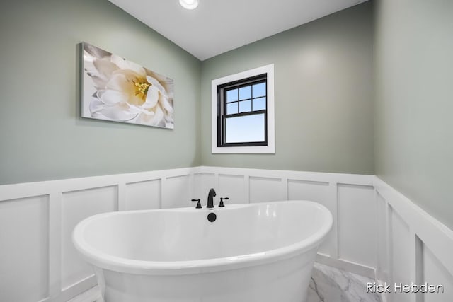 1153 S Edgar Rd, Mason, MI 48854 - bathroom featuring a decorative wall, marble finish flooring, a soaking tub, and a wainscoted wall