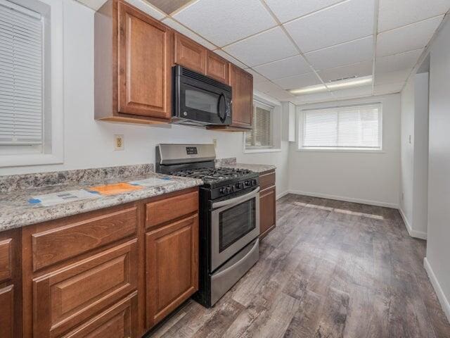 1516 Nazareth Rd, Kalamazoo, MI 49048 - kitchen featuring stainless steel gas stove, black microwave, light wood-style flooring, brown cabinetry, and a drop ceiling