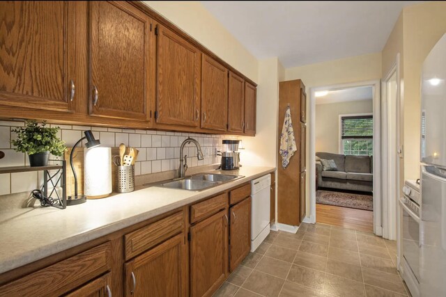 1307 Edgewood Ave, Ann Arbor, MI 48103 - kitchen with white dishwasher, brown cabinets, light countertops, decorative backsplash, and light tile patterned floors