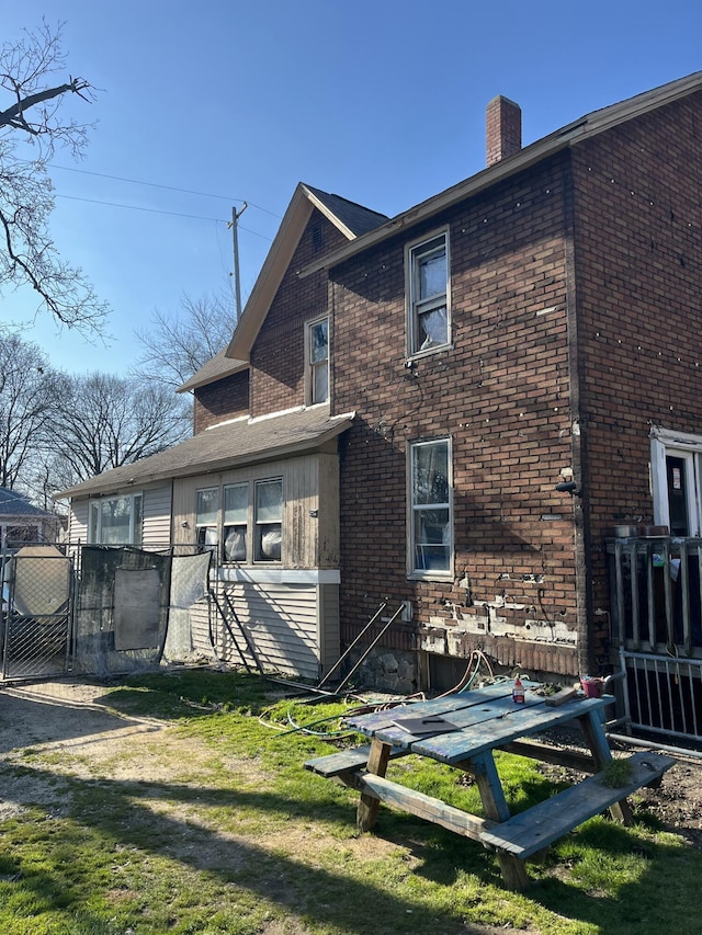 928 Trimble Ave, Kalamazoo, MI 49048 - back of house with a chimney, a yard, brick siding, and a gate