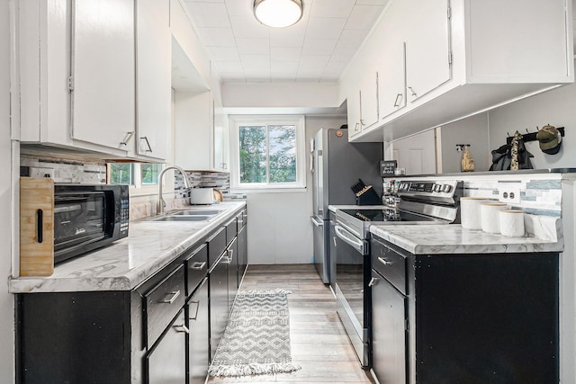 5468 S Custer Rd, Custer, MI 49405 - kitchen with electric range, white cabinetry, dark cabinetry, light wood-style floors, and light countertops