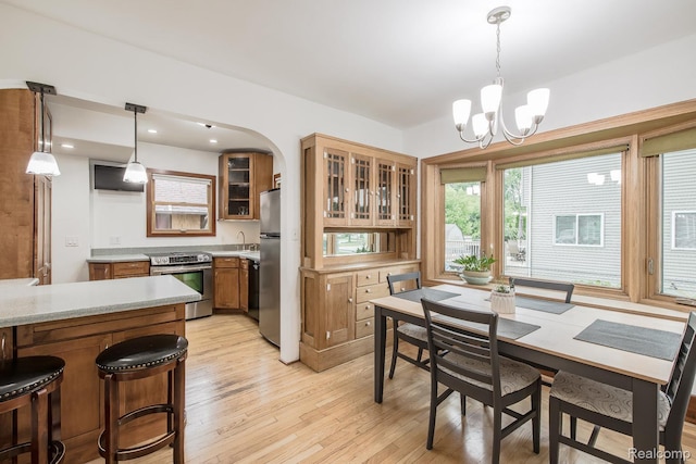 284 W Clarkston Rd, Lake Orion, MI 48362 - dining room featuring light wood finished floors, a chandelier, and arched walkways