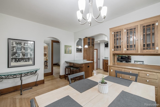 284 W Clarkston Rd, Lake Orion, MI 48362 - dining space with arched walkways, a chandelier, and light wood-style floors