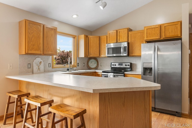 2973 Riley Ridge Rd, Holland, MI 49424 - kitchen featuring appliances with stainless steel finishes, a peninsula, light countertops, light wood-type flooring, and lofted ceiling