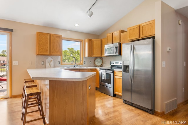 2973 Riley Ridge Rd, Holland, MI 49424 - kitchen with appliances with stainless steel finishes, light wood-style floors, backsplash, light countertops, and a kitchen bar