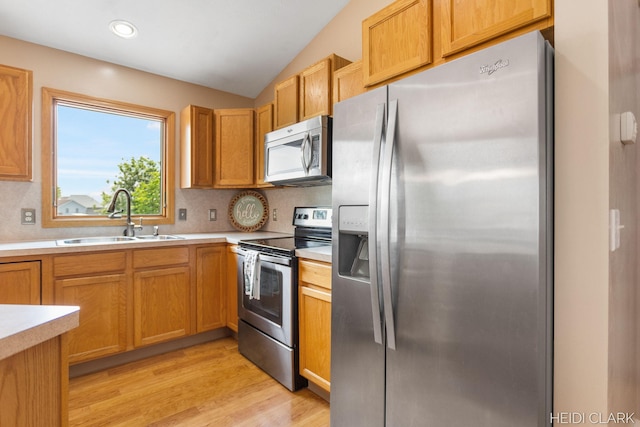 2973 Riley Ridge Rd, Holland, MI 49424 - kitchen with stainless steel appliances, light countertops, vaulted ceiling, light wood-type flooring, and tasteful backsplash