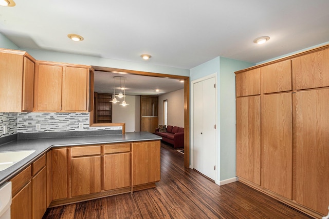 522 Lyon St, South Haven, MI 49090 - kitchen with dark wood-type flooring, a peninsula, dark countertops, tasteful backsplash, and hanging light fixtures