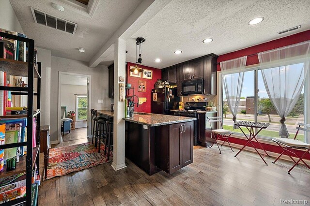 1769 W Warren Ave, Detroit, MI 48208 - kitchen with black appliances, wood finished floors, dark brown cabinets, stone countertops, and a textured ceiling