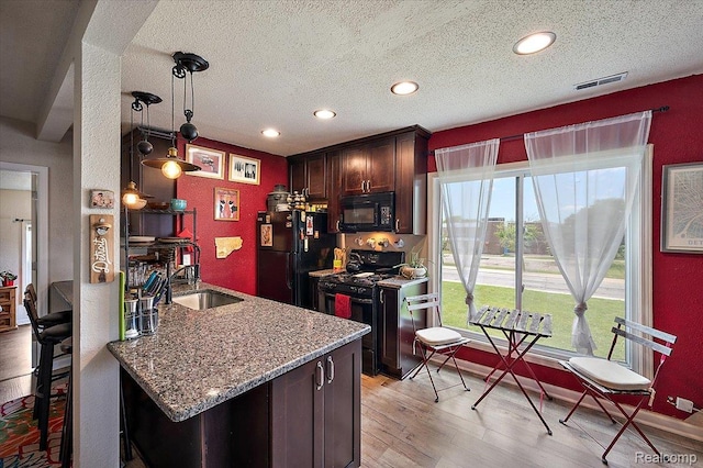 1769 W Warren Ave, Detroit, MI 48208 - kitchen with black appliances, a textured ceiling, recessed lighting, light stone counters, and light wood-type flooring