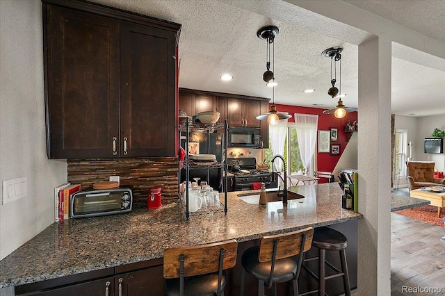 1769 W Warren Ave, Detroit, MI 48208 - kitchen with black appliances, a textured ceiling, dark brown cabinetry, a peninsula, and recessed lighting