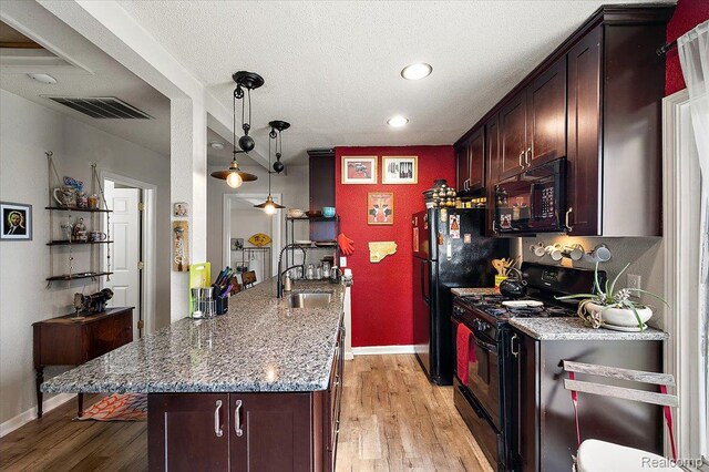 1769 W Warren Ave, Detroit, MI 48208 - kitchen featuring black appliances, light stone counters, light wood-style flooring, dark brown cabinets, and a peninsula