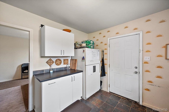 1769 W Warren Ave, Detroit, MI 48208 - kitchen with freestanding refrigerator, dark countertops, wallpapered walls, white cabinets, and dark stone finish floors