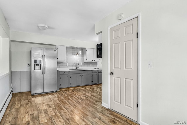 338 Cherry St, Blissfield, MI 49228 - kitchen with stainless steel fridge with ice dispenser, baseboard heating, gray cabinetry, wood finished floors, and backsplash