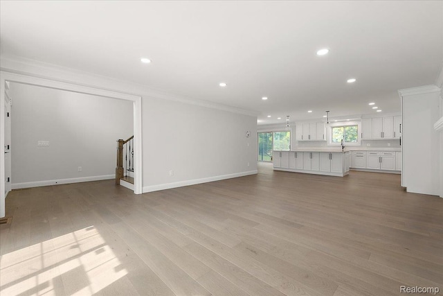 56350 Willow Creek Blvd, Utica, MI 48316 - unfurnished living room featuring crown molding, recessed lighting, light wood-style floors, and stairs