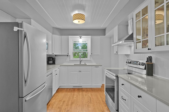 8475 Homerich Ave SW, Byron Center, MI 49315 - kitchen featuring appliances with stainless steel finishes, wall chimney exhaust hood, white cabinetry, light wood finished floors, and light countertops