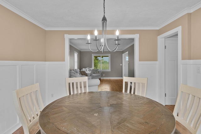 8475 Homerich Ave SW, Byron Center, MI 49315 - dining space with a chandelier, crown molding, wood finished floors, a wainscoted wall, and a decorative wall
