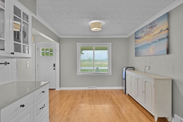 8475 Homerich Ave SW, Byron Center, MI 49315 - unfurnished dining area with light wood finished floors, a textured ceiling, and ornamental molding