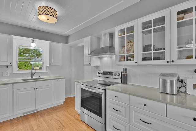 8475 Homerich Ave SW, Byron Center, MI 49315 - kitchen with stainless steel electric stove, wall chimney range hood, light wood finished floors, white cabinets, and glass insert cabinets