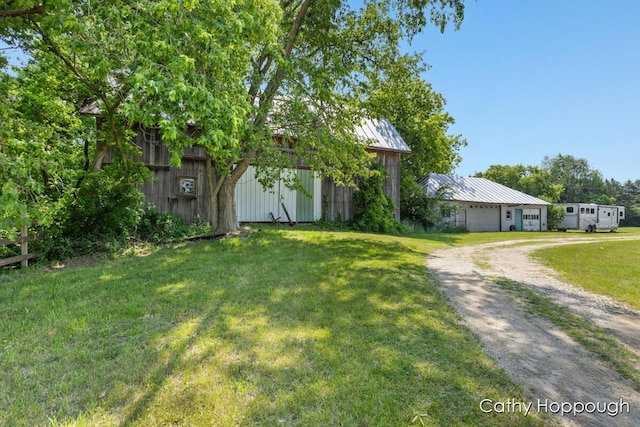 3119 S Hillman Rd, Sidney, MI 48885 - view of front of home featuring driveway, an outbuilding, a front lawn, a standing seam roof, and a metal roof