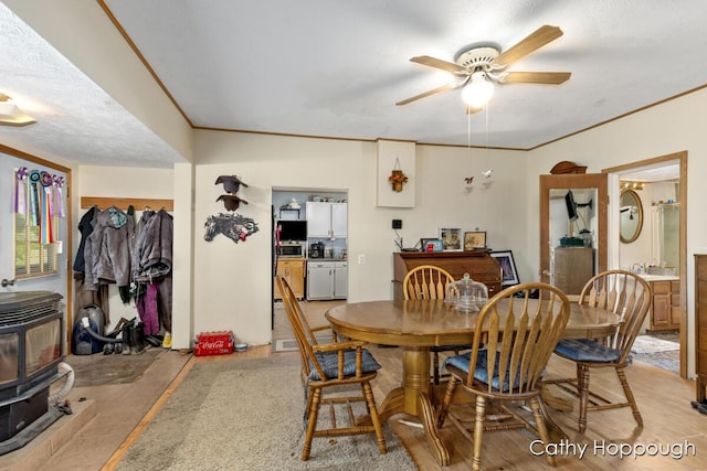 3119 S Hillman Rd, Sidney, MI 48885 - dining area featuring a wood stove, ceiling fan, and ornamental molding