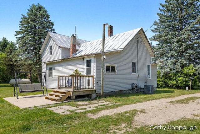 3119 S Hillman Rd, Sidney, MI 48885 - rear view of property with a chimney, a yard, a standing seam roof, a wooden deck, and a metal roof