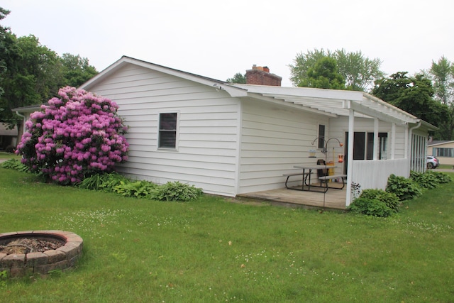 229 Riverside Dr, Hart, MI 49420 - view of property exterior featuring a chimney, a lawn, and an outdoor fire pit