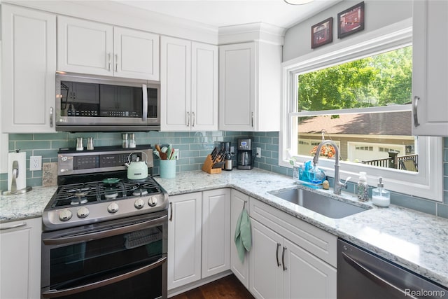 20551 Elwell Rd, Belleville, MI 48111 - kitchen featuring appliances with stainless steel finishes, white cabinetry, decorative backsplash, and light stone countertops