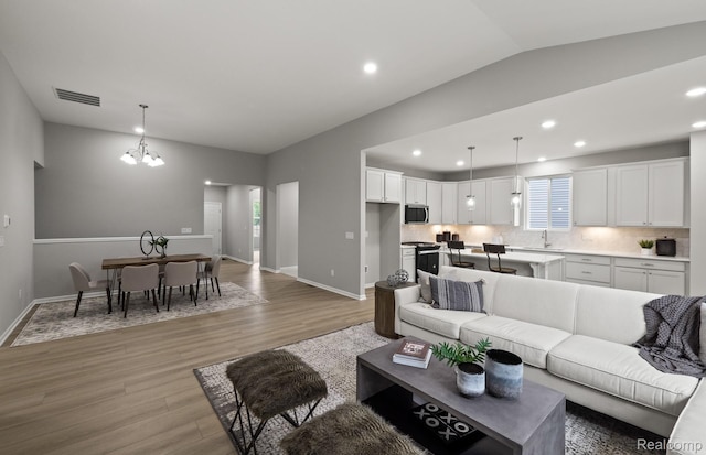 3045 Sheffield Cir, Clarkston, MI 48346 - living room with light wood-type flooring, a chandelier, lofted ceiling, and recessed lighting