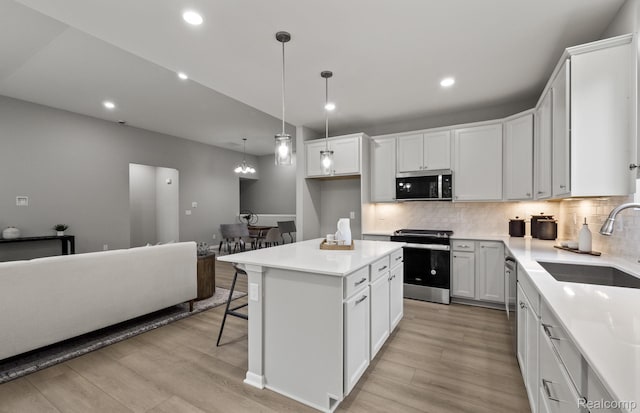 3045 Sheffield Cir, Clarkston, MI 48346 - kitchen featuring stainless steel appliances, light wood-type flooring, tasteful backsplash, a breakfast bar, and a kitchen island