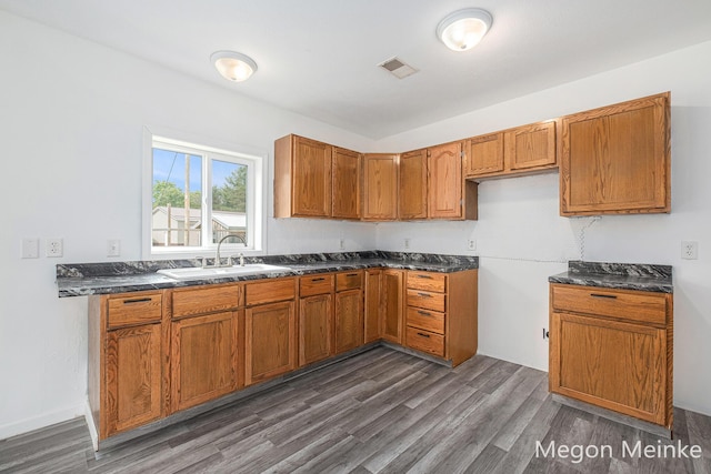 3682 W Long Lake Rd, Orleans, MI 48865 - kitchen featuring dark countertops, brown cabinetry, and dark wood-type flooring