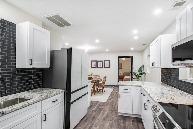 6490 Island Lake Rd, Holland, MI 49423 - kitchen with stainless steel appliances, a peninsula, white cabinetry, dark wood-type flooring, and recessed lighting