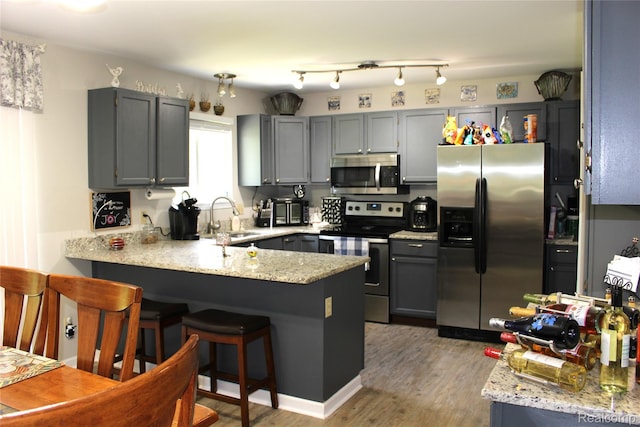 14361 Blue Heron Dr, Fenton, MI 48430 - kitchen featuring appliances with stainless steel finishes, a peninsula, gray cabinetry, light wood-style floors, and light stone counters