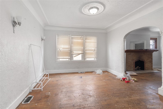 17327 Indiana St, Detroit, MI 48221 - unfurnished living room with healthy amount of natural light, a fireplace, hardwood / wood-style flooring, arched walkways, and a textured ceiling