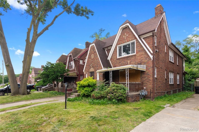 17327 Indiana St, Detroit, MI 48221 - tudor house with brick siding, a chimney, a front yard, and roof with shingles