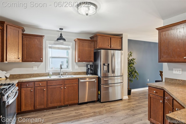 1123 Tartan Ln, Walled Lake, MI 48390 - kitchen featuring appliances with stainless steel finishes, light wood finished floors, pendant lighting, and brown cabinetry
